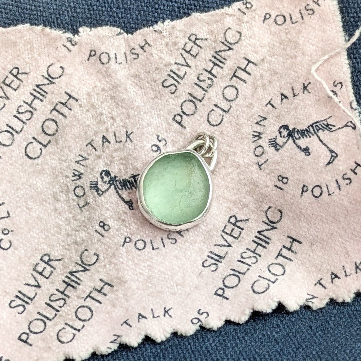 Seafoam sea glass silver pendant on workbench after polish