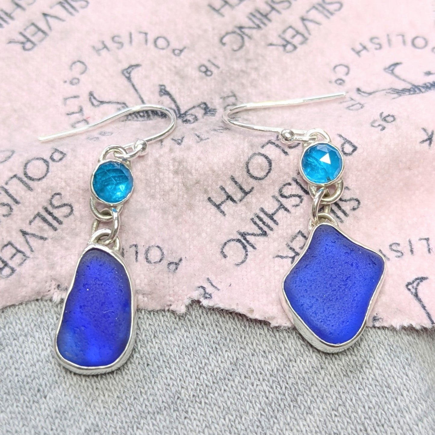 Danglyblueseaglassandgemstoneapatitesilverearringsonpolishingcloth