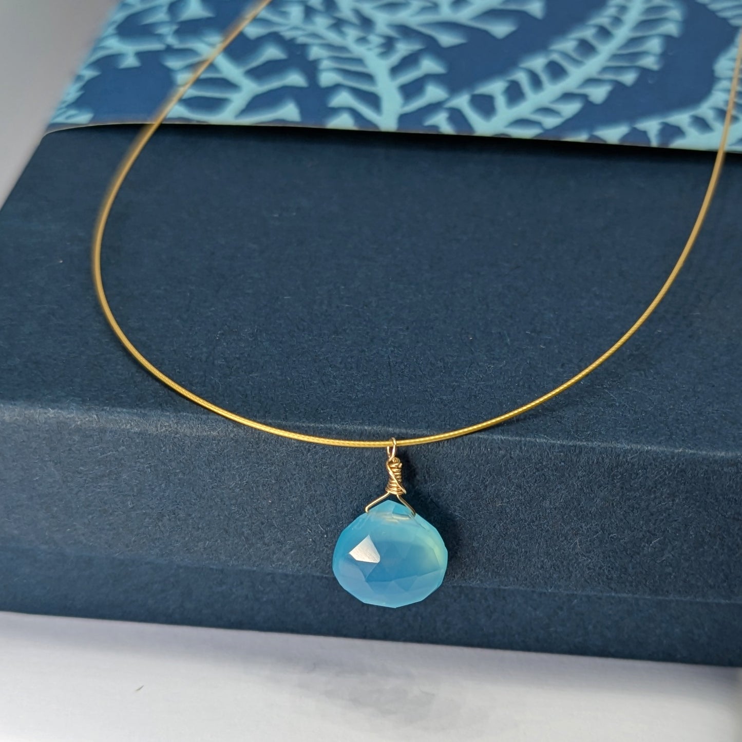 Blue gemstone and gold drop pendant. Cornish Blue Sky Drop Pendant on blue gift box