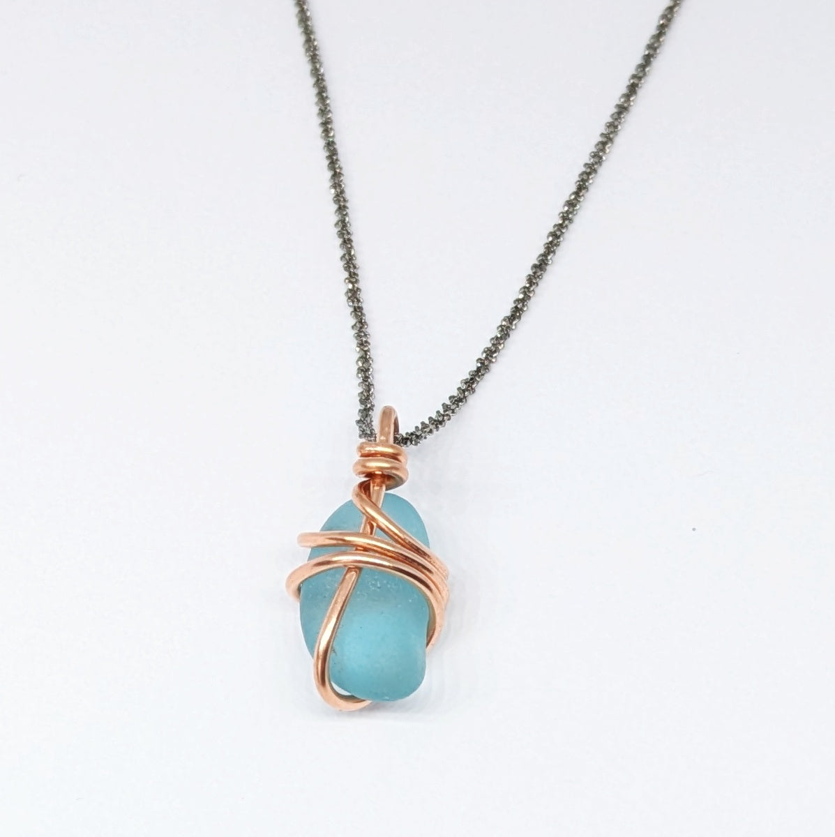 Back view of Turquoise sea glass wrapped in copper pendant on white background