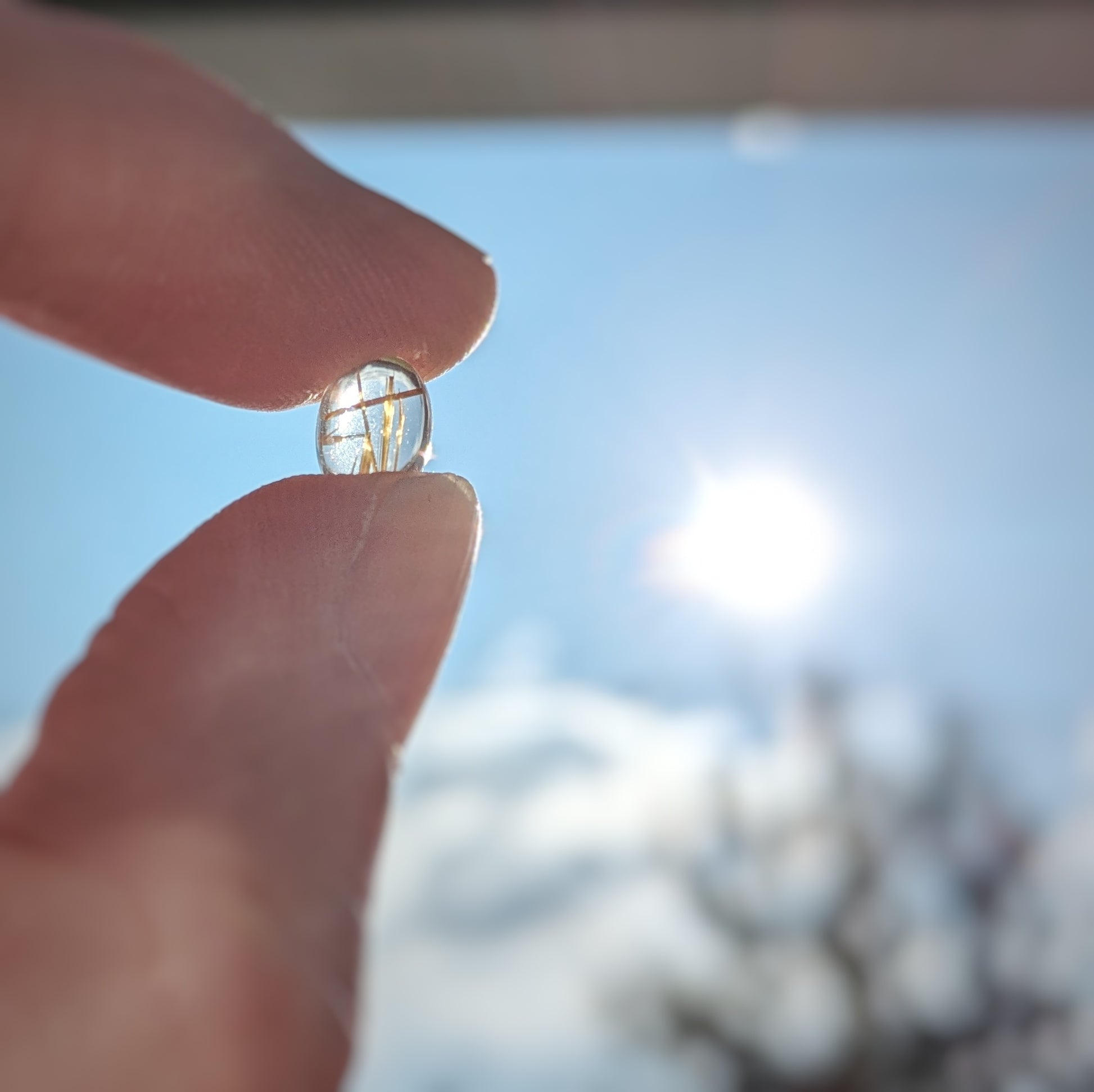 Golden Sparkle Quartz pendant in sterling silver held up to the blue sky