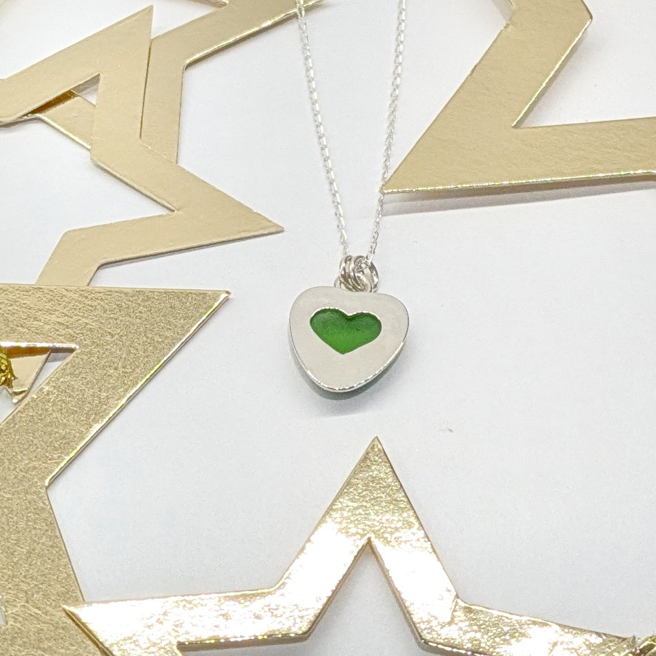 Green Sea Glass silver pendant with heart shape cut out, with silver chain and festive gold star decorations.