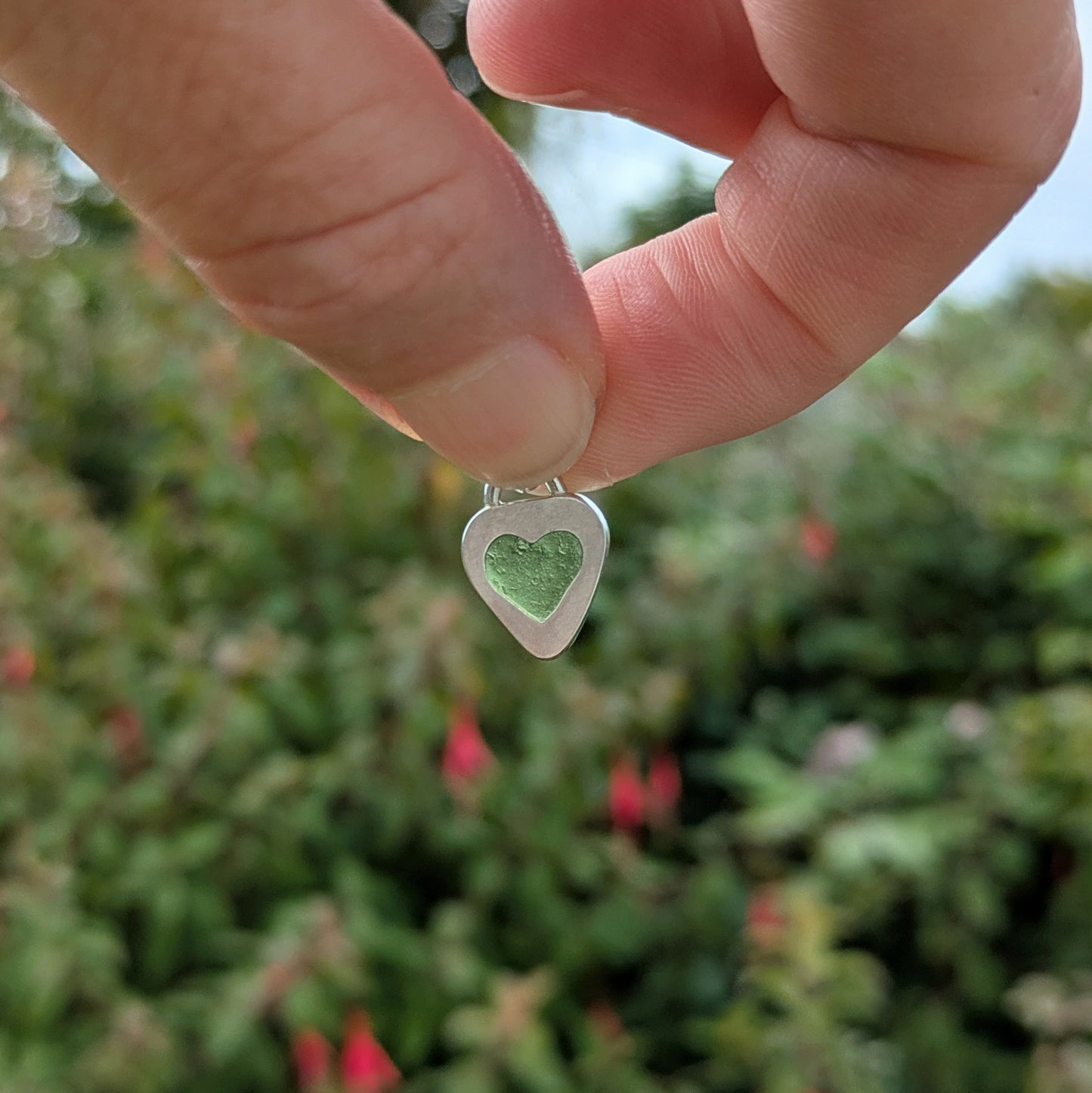 Hand holding heart shaped sea glass silver pendant