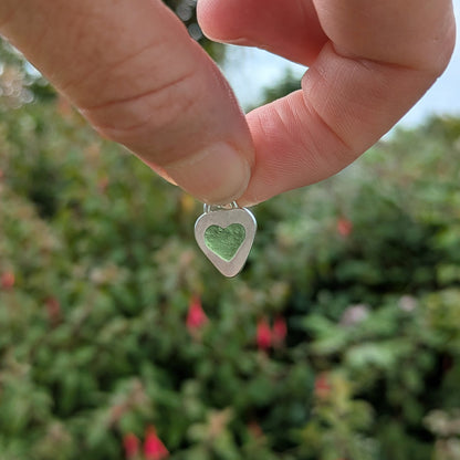 Hand holding heart shaped sea glass silver pendant