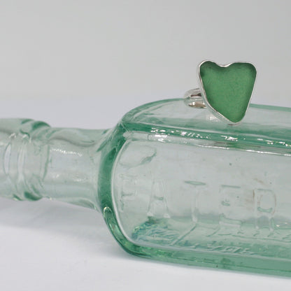 Heart of Green Sea Glass Ring sitting on old glass bottle