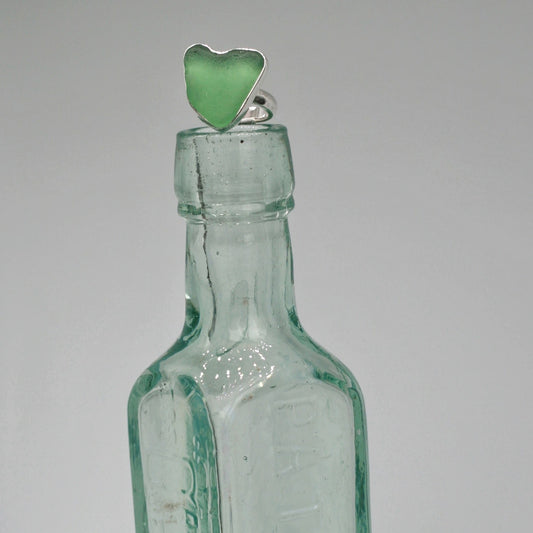 Heart of Green Sea Glass Ring sitting on old glass bottle