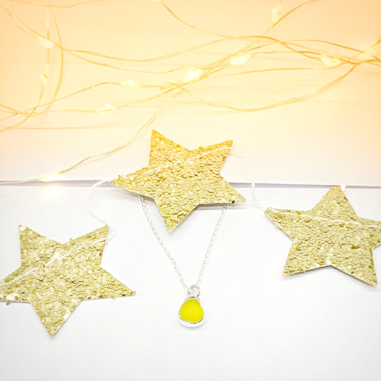 Rare yellow sea glass silver pendant with gold star festive background.