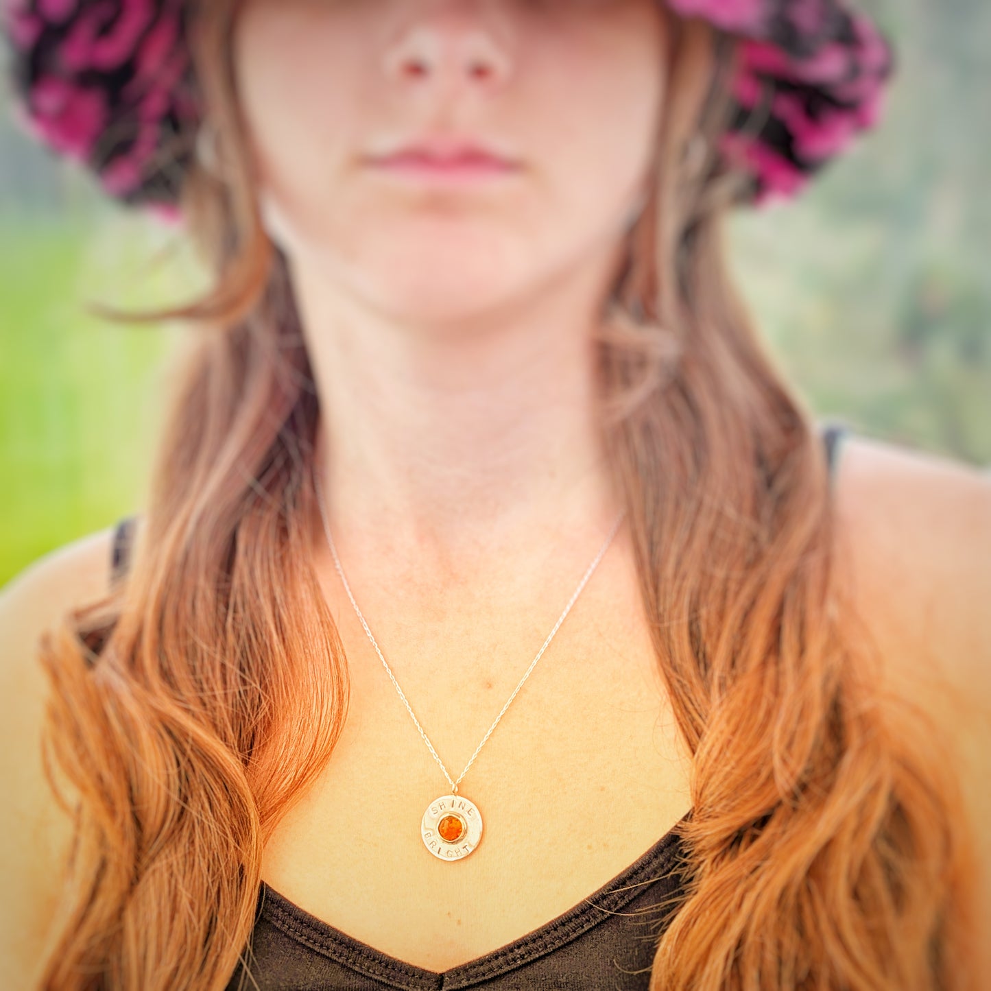 Handmade recycled silver circle pendant, featuring the words ' Shine Bright' around a central golden citrine gemstone.  Picture shows model wearing pendant.