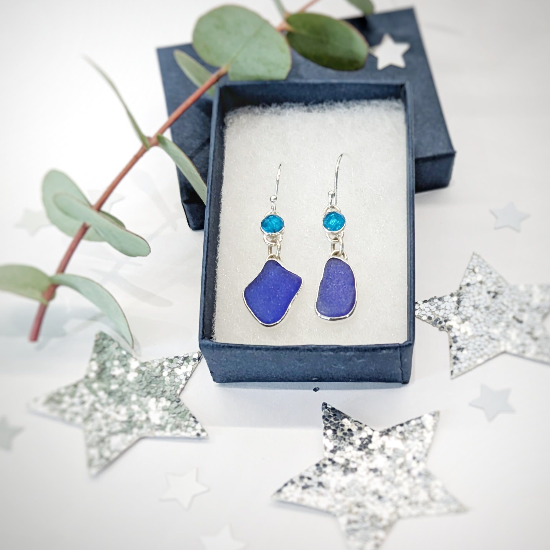 Blue sea glass and gemstone apatite silver drop earrings in Nicola Prophet Jewellery gift box with festive background