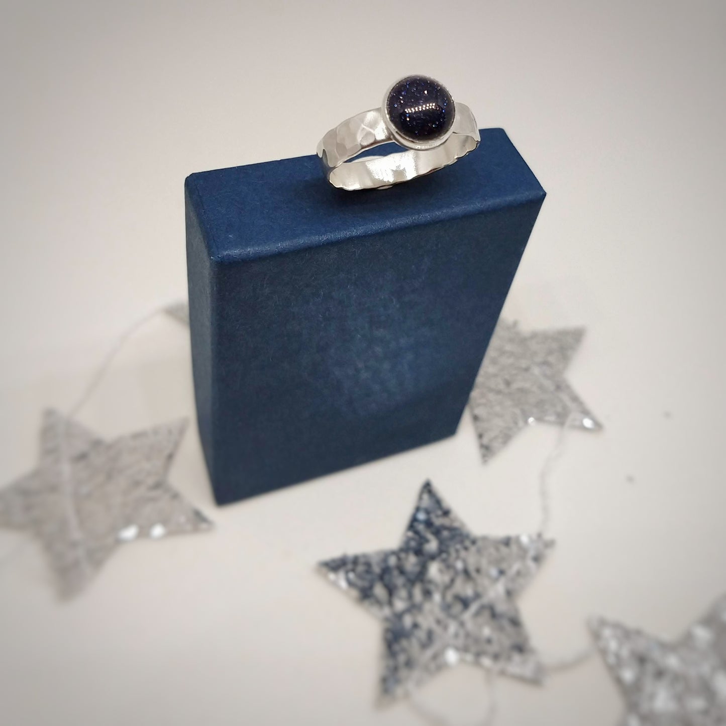 Blue Goldstone Silver Hammered Ring sitting on blue gift box surrounded by silver stars