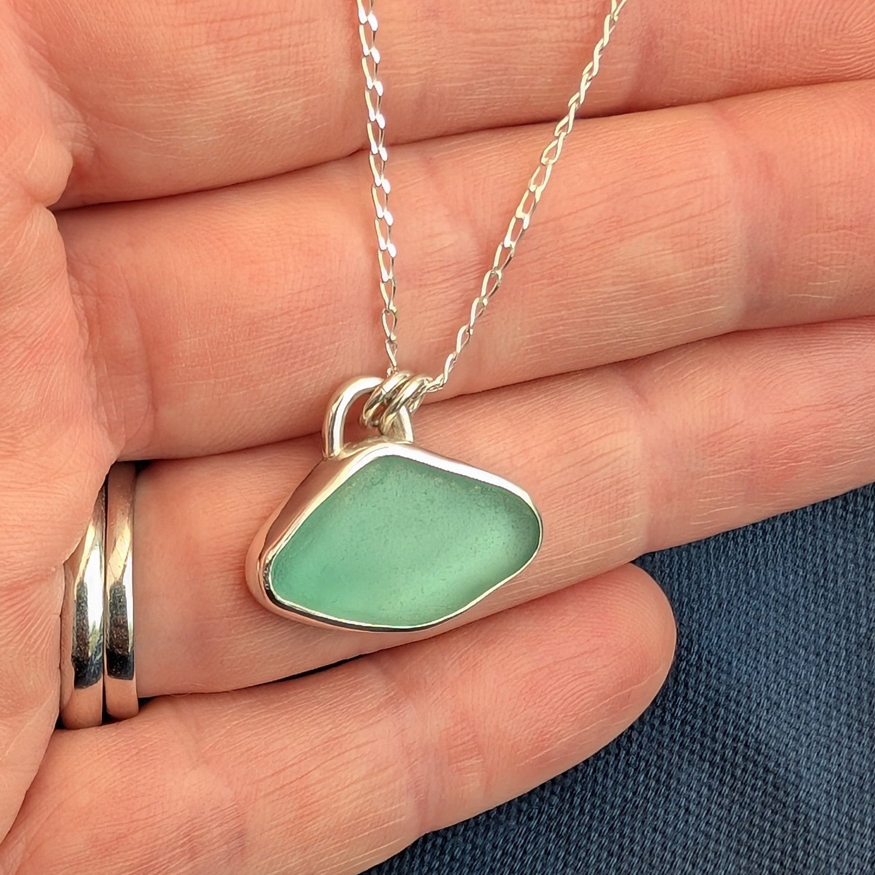 Soft Aqua Cornish sea glass and silver pendant necklace on silver chain in hand