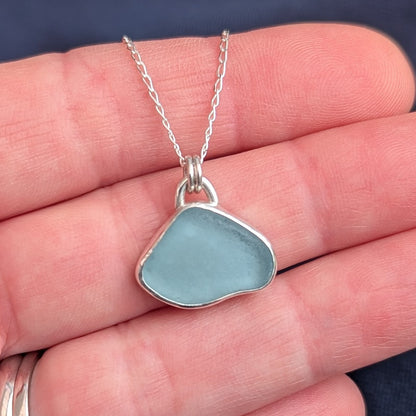 Pale Blue Cornish Sea Glass set in recycled silver with silver chain sitting in hand