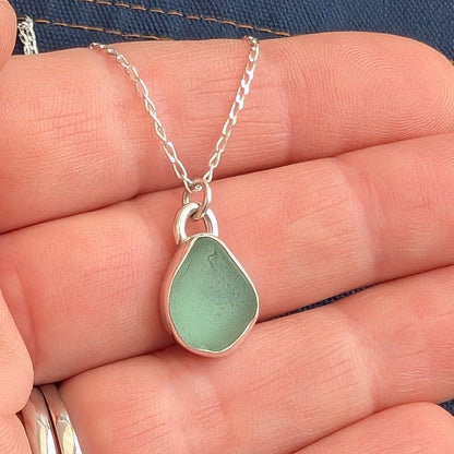 Seafoam Cornish sea glass and silver drop pendant necklace on silver chain in hand