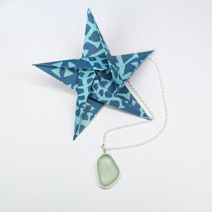Blue origami star next to Seafoam sea glass silver pendant