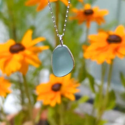 Seafoam sea glass silver pendant with yellow flowers in background