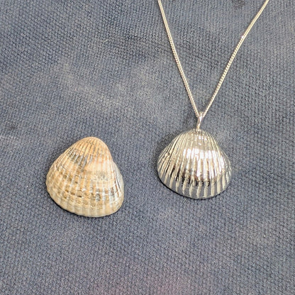 Pure Silver sea shell pendant cast from a real sea shell next to the original sea shell