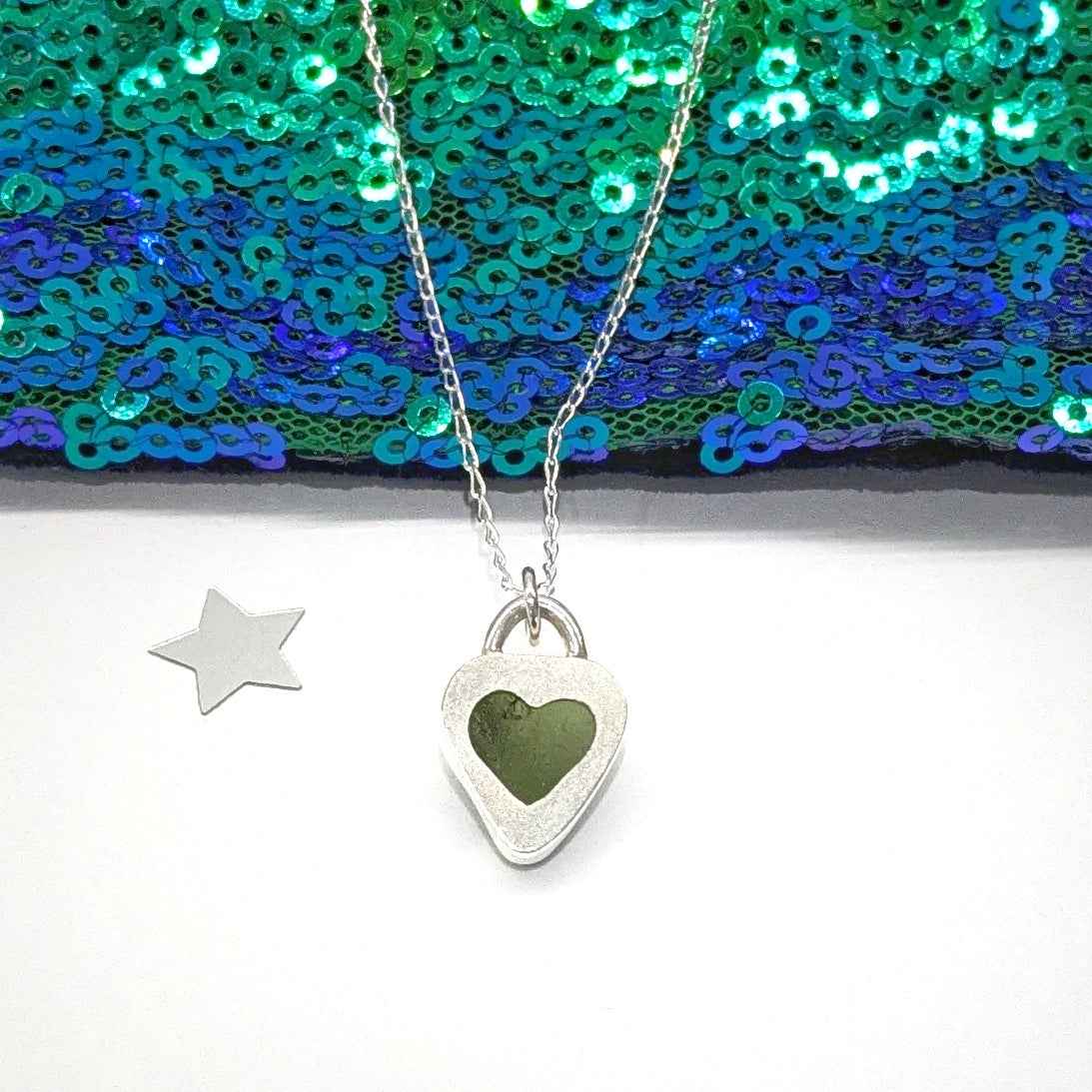St Ives Green sea glass silver pendant with heart shaped cut out on silver chain, with festive background.