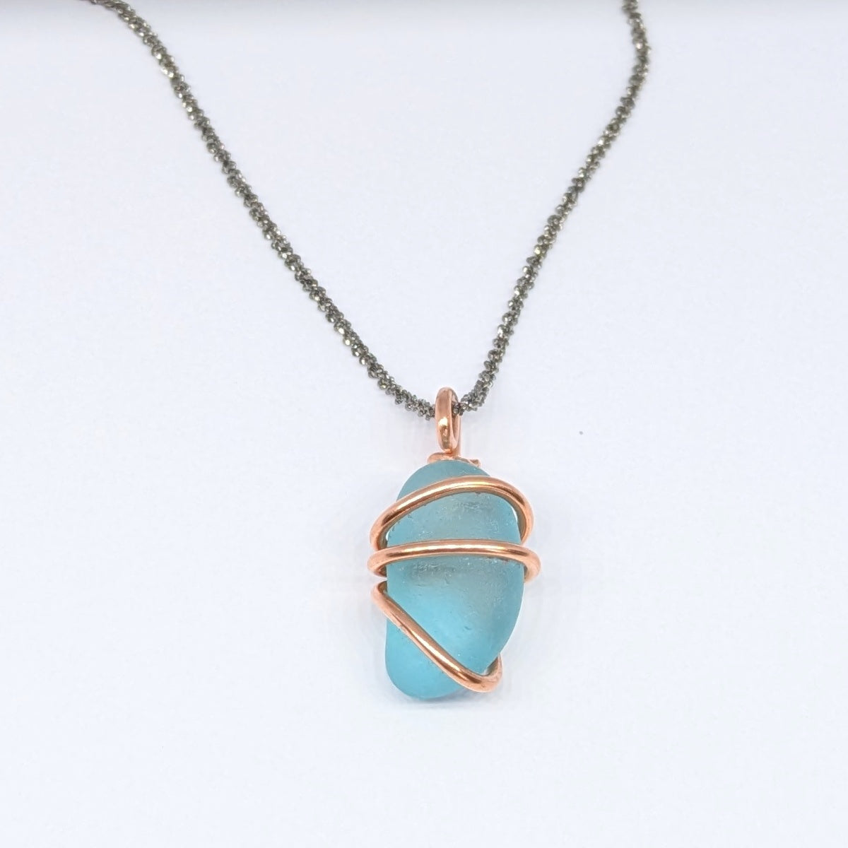 Front view on white background of Turquoise sea glass wrapped in copper pendant