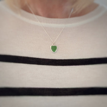 Model in stripey top wearing Green Sea Glass silver pendant with heart shape cut out, with silver chain 