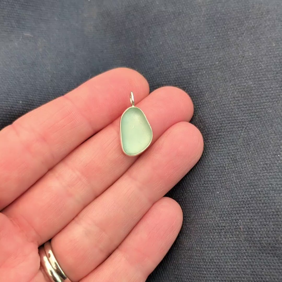 video of hand holding Seafoam sea glass silver pendant