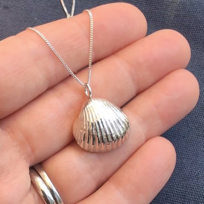 Video of hand holding pure silver sea shell pendant