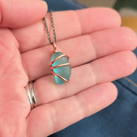 Turquoise sea glass wrapped in copper pendant in hand video