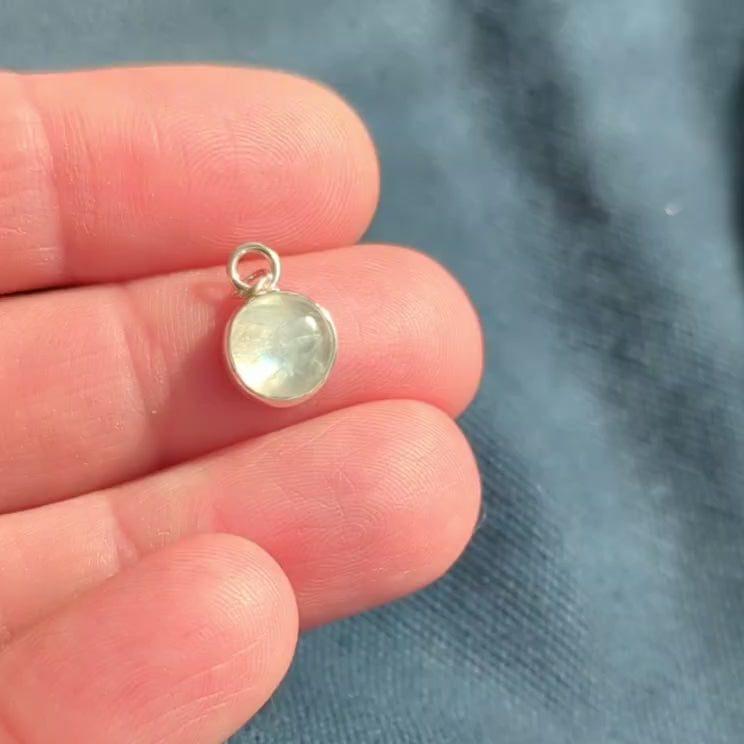 Video of smooth Snowball Moonstone pendant set in sterling silver in hand