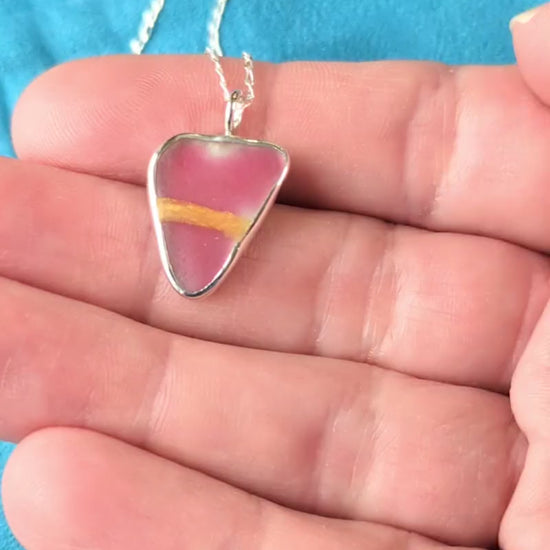 Red Sea Glass silver pendant with gold Kintsugi repair, on chain, in hand.