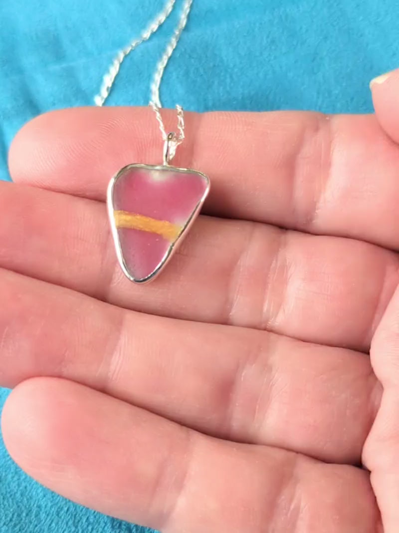 Red Sea Glass silver pendant with gold Kintsugi repair, on chain, in hand.