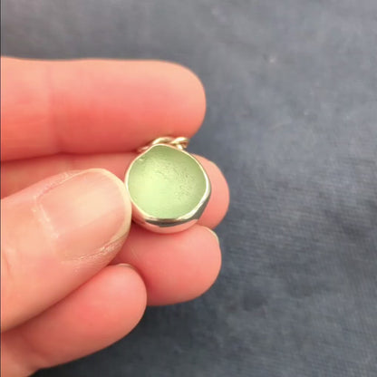 Hand holding and showing Seafoam sea glass silver pendant