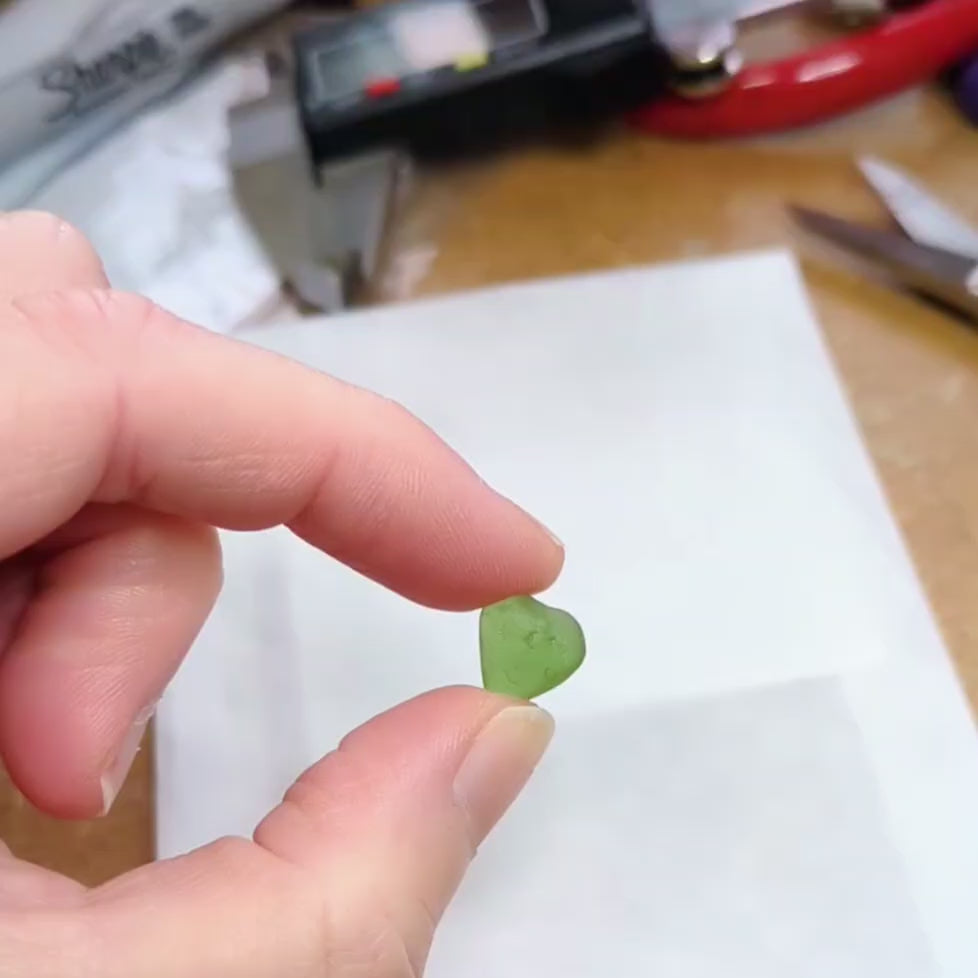 Hand holding little green sea glass heart