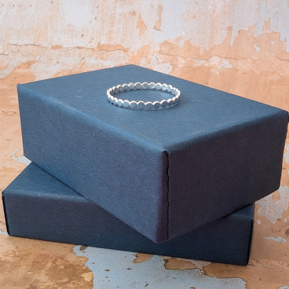 Tiny pebbles hammered silver ring on blue box
